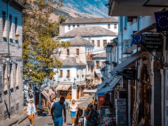 a group of people walking down a street next to tall buildings
