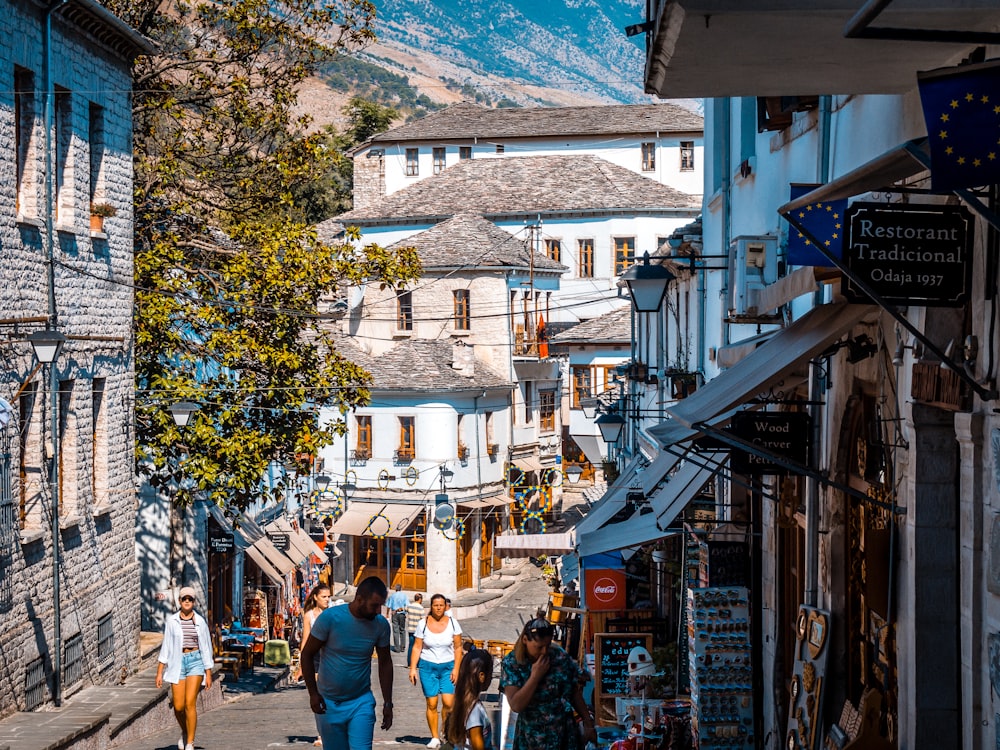 a group of people walking down a street next to tall buildings