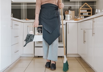 a woman standing in a kitchen holding a broom