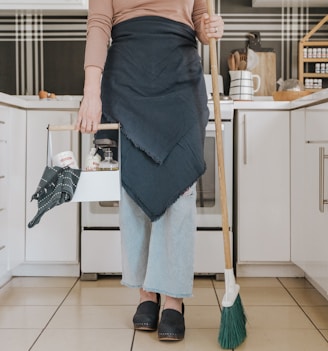 a woman standing in a kitchen holding a broom