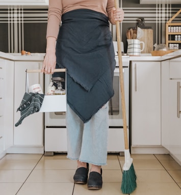 a woman standing in a kitchen holding a broom