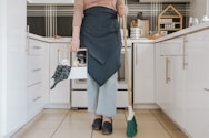 a woman standing in a kitchen holding a broom