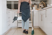 a woman standing in a kitchen holding a broom