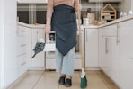 a woman standing in a kitchen holding a broom