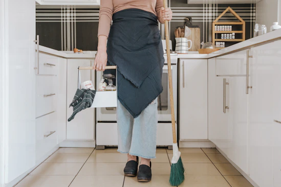 A professional cleaner gently dusting a bright and tidy kitchen space.