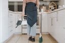 a woman standing in a kitchen holding a broom