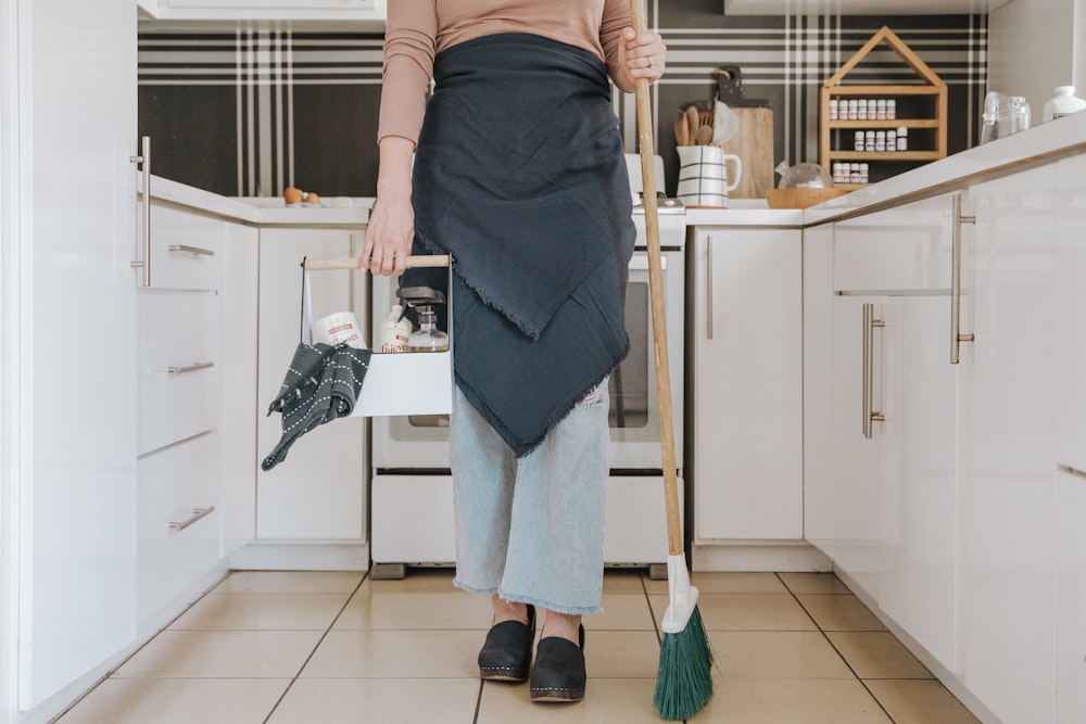 una donna in piedi in una cucina con in mano una scopa