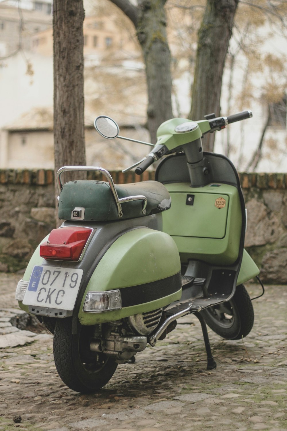 a green scooter parked on a cobblestone street