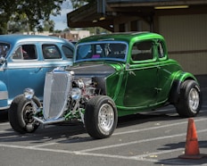 a green car parked next to a blue car in a parking lot