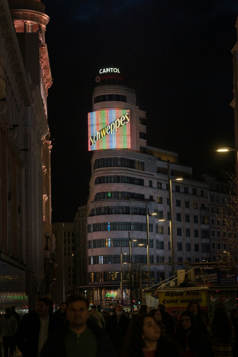 a crowd of people walking down a street at night