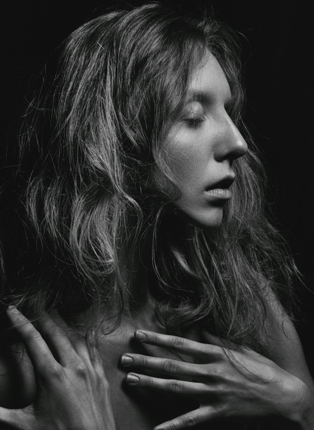a black and white photo of a woman with her hands on her chest