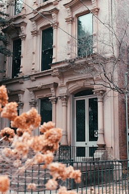 a building with a fence and flowers in front of it