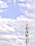 A telecommunications tower stands against a backdrop of a partly cloudy sky. The structure is equipped with various antennas and equipment, suggesting its use for communication purposes.