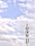 A telecommunications tower stands against a backdrop of a partly cloudy sky. The structure is equipped with various antennas and equipment, suggesting its use for communication purposes.