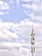 A telecommunications tower stands against a backdrop of a partly cloudy sky. The structure is equipped with various antennas and equipment, suggesting its use for communication purposes.