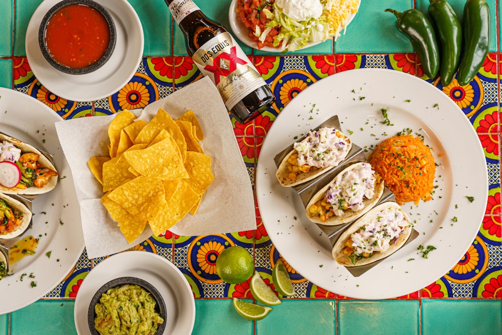 a table topped with plates of tacos and guacamole