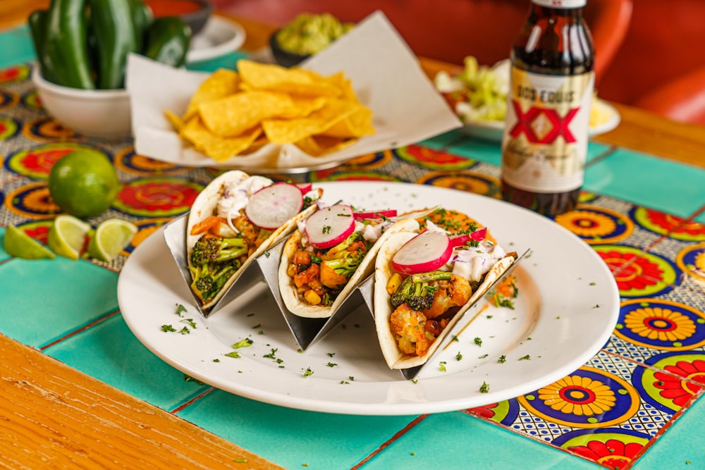 a plate of tacos and a bottle of beer on a table