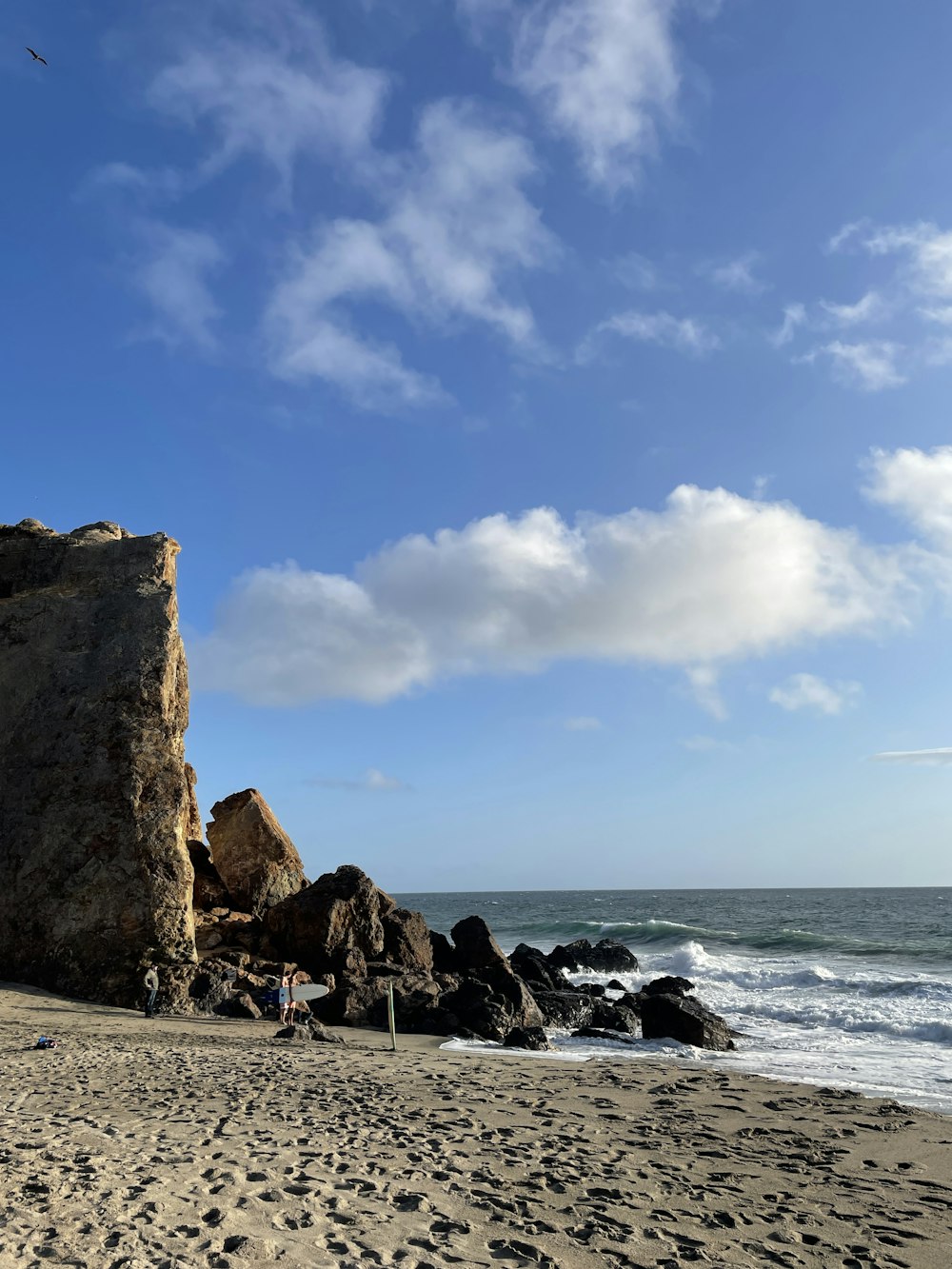 a sandy beach next to the ocean under a blue sky