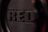 Close-up view of a textured surface with the word 'RED' embossed on it, featuring a detailed pattern of tiny raised dots and grooves. The focus creates a sense of depth and dimension.