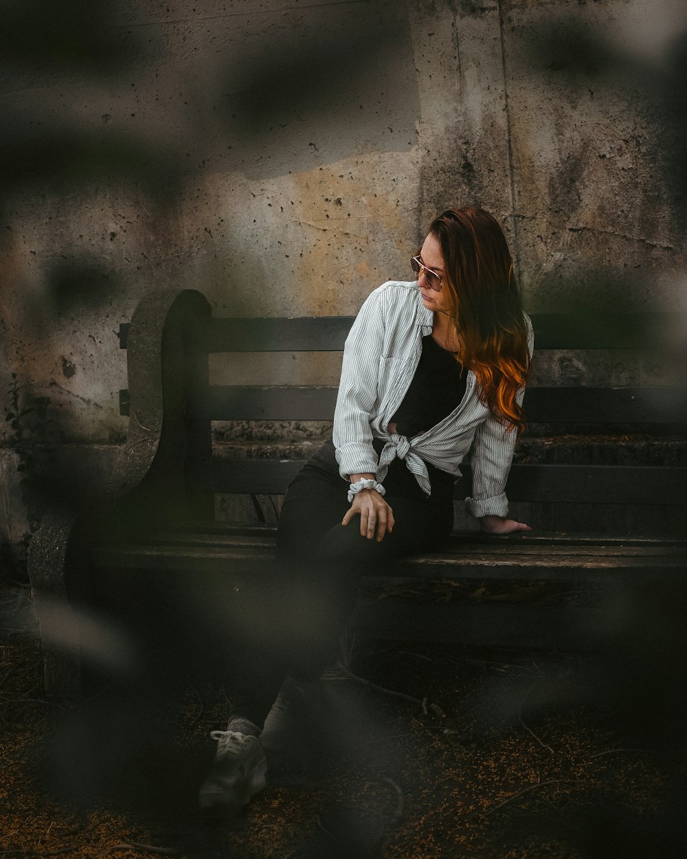 a woman sitting on a bench in front of a wall