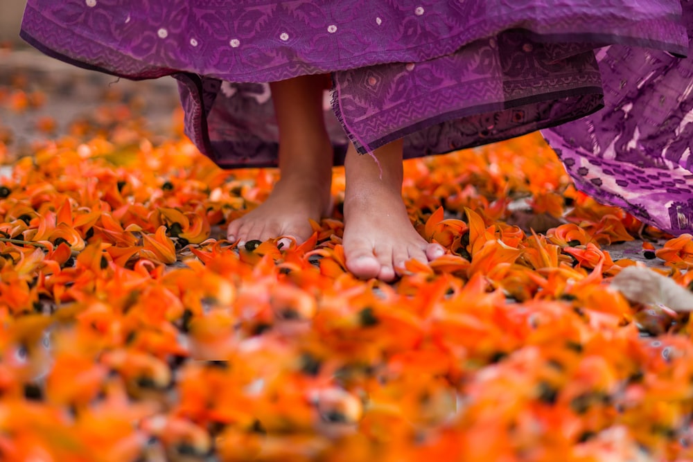 a close up of a person's feet in a field of orange flowers
