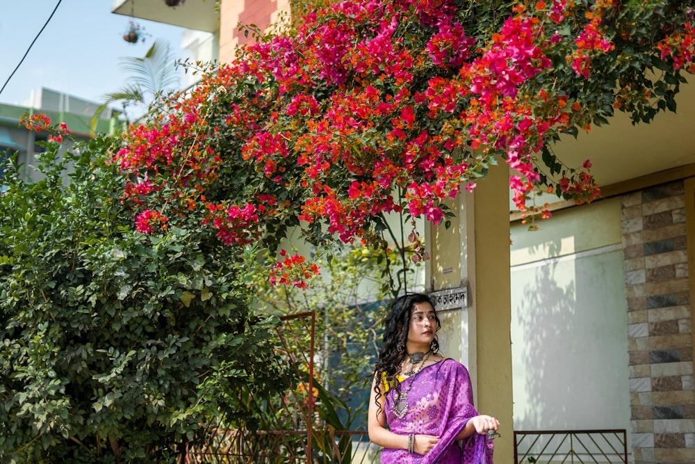 a woman in a purple sari standing in front of a house