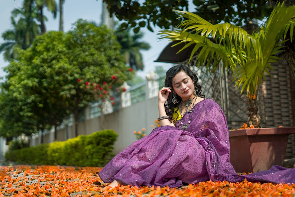 a woman sitting on the ground in a purple dress