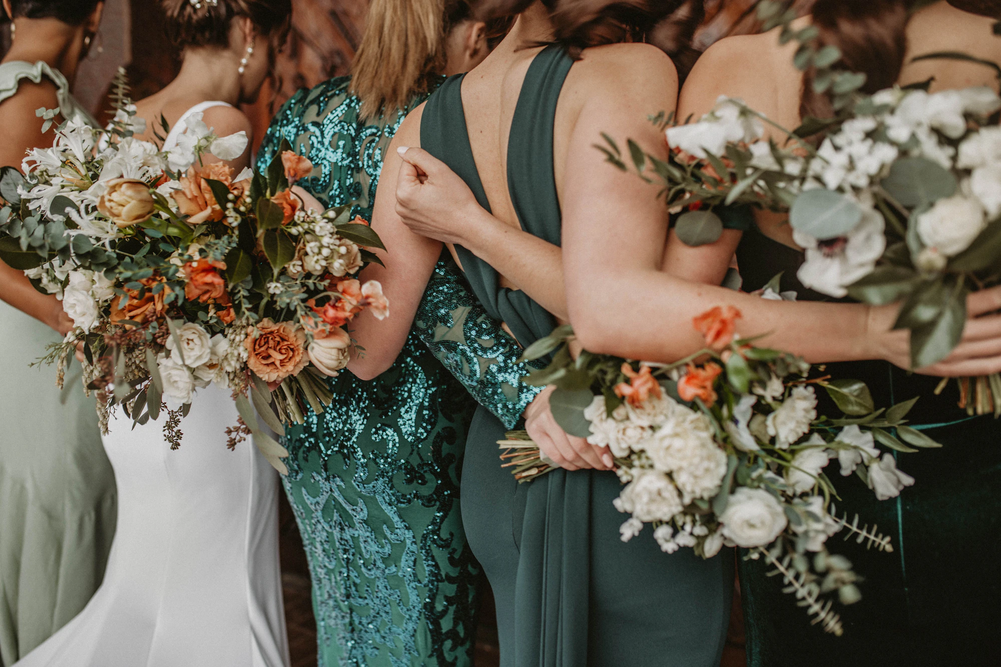 Bridesmaids in emerald dresses holding bouquets
