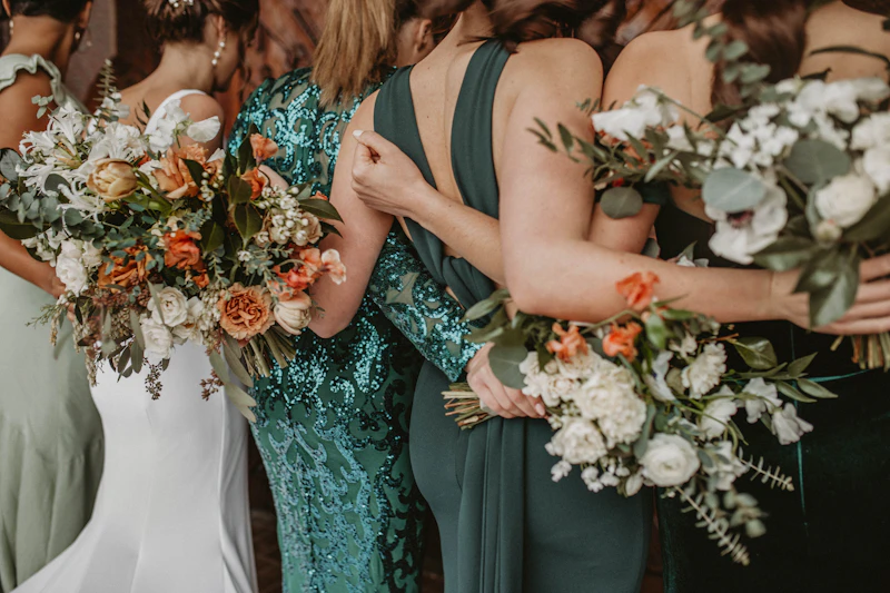 Bridesmaids in emerald dresses holding bouquets