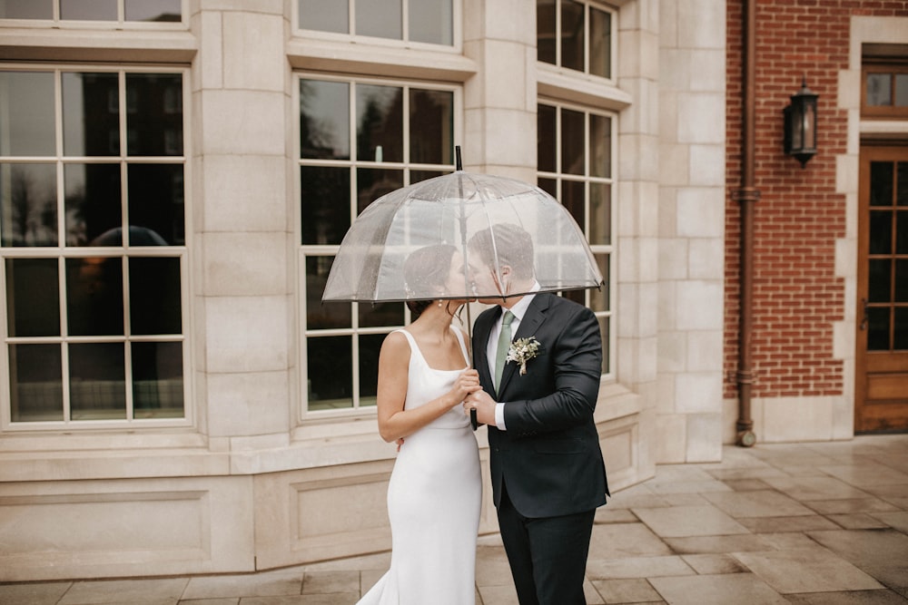 a bride and groom standing under an umbrella