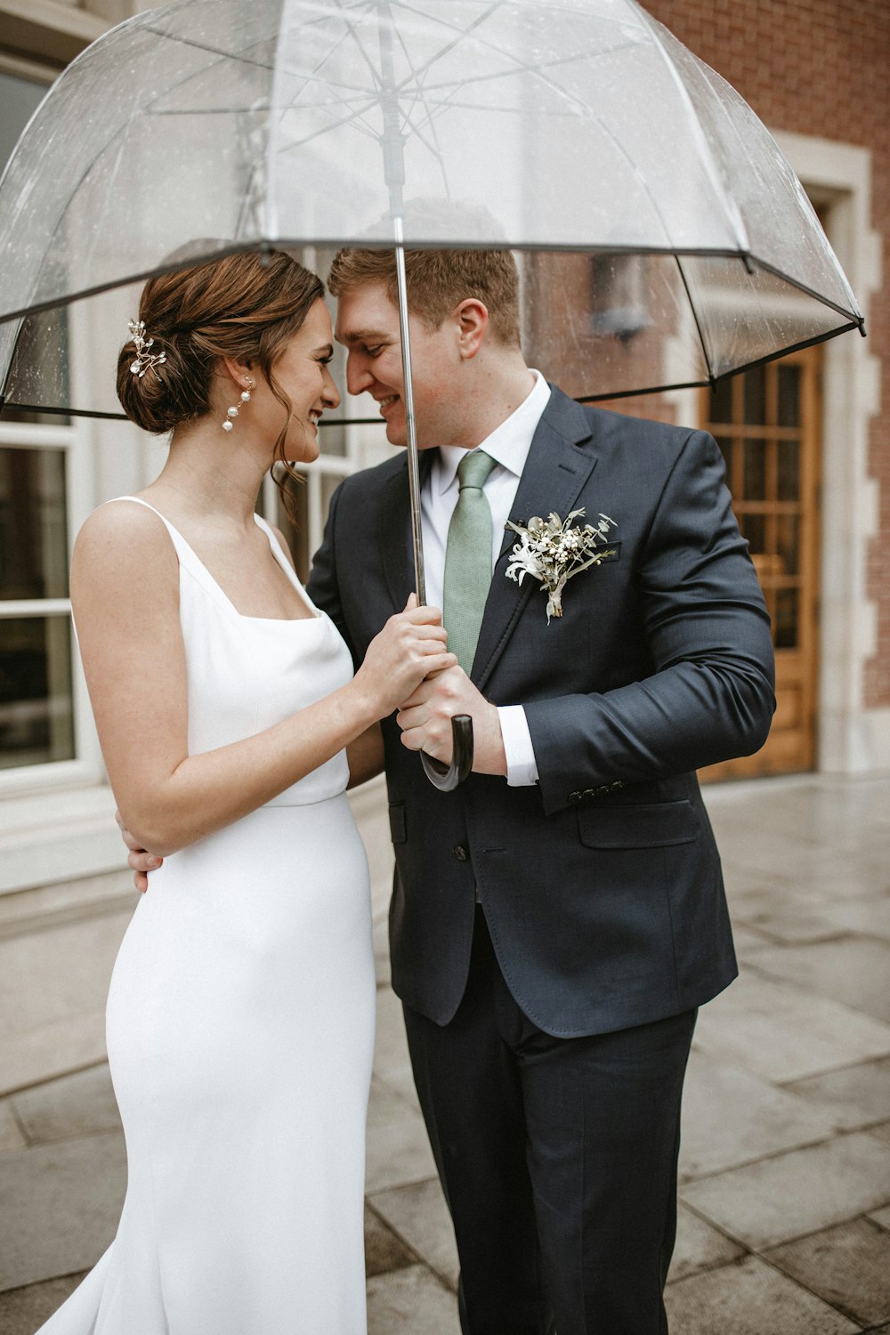 a bride and groom standing under an umbrella