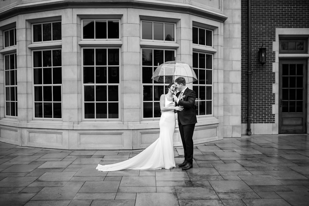 a bride and groom standing under an umbrella