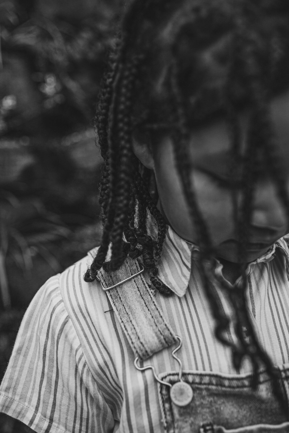 a woman with dreadlocks standing in front of a tree