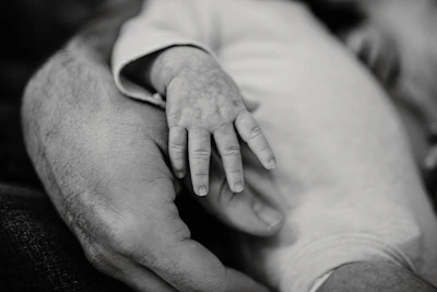 A gentle close-up of a parent's hand holding a baby's tiny hand, symbolizing care and trust.