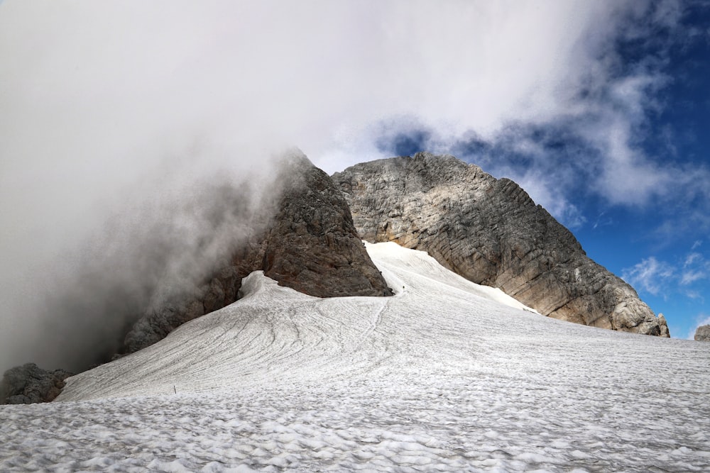 a snow covered mountain under a cloudy blue sky