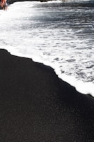 a group of people walking along a beach next to the ocean