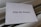 A piece of white paper with the words 'Pray for Ukraine' typed in a bold, black font is placed on a soft, light-colored fabric background.