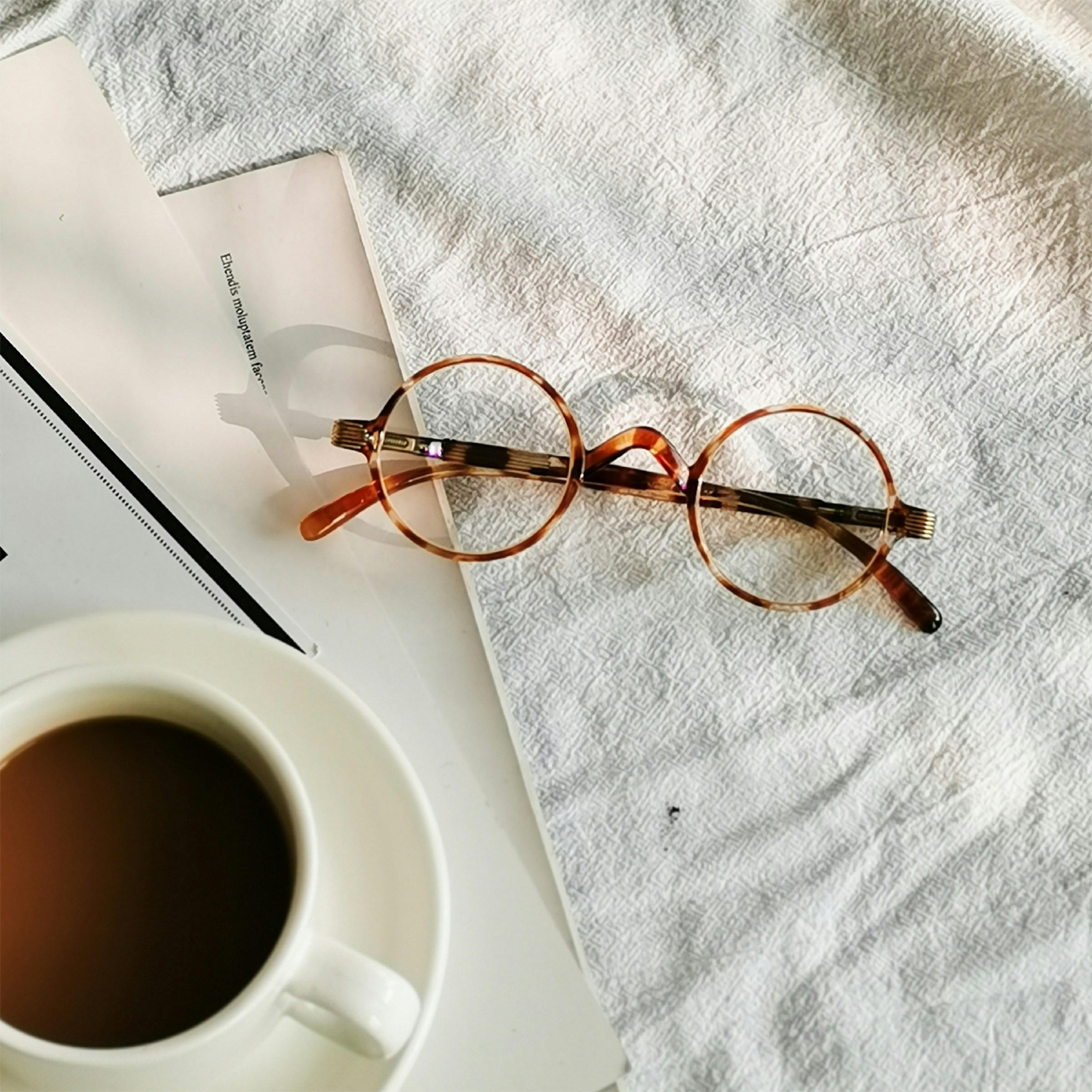 a pair of glasses sitting on top of a table next to a cup of