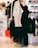 A person is selecting a white coat decorated with artistic drawings in a clothing store. The setting includes various apparel items such as hats, shoes, and jackets displayed on shelves and racks. The store has a modern ambiance with bright lighting.