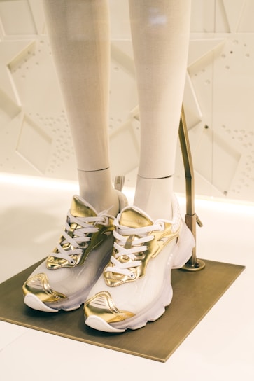 Close-up of trendy black and white sneakers with gold accents displayed on a sleek shelf.