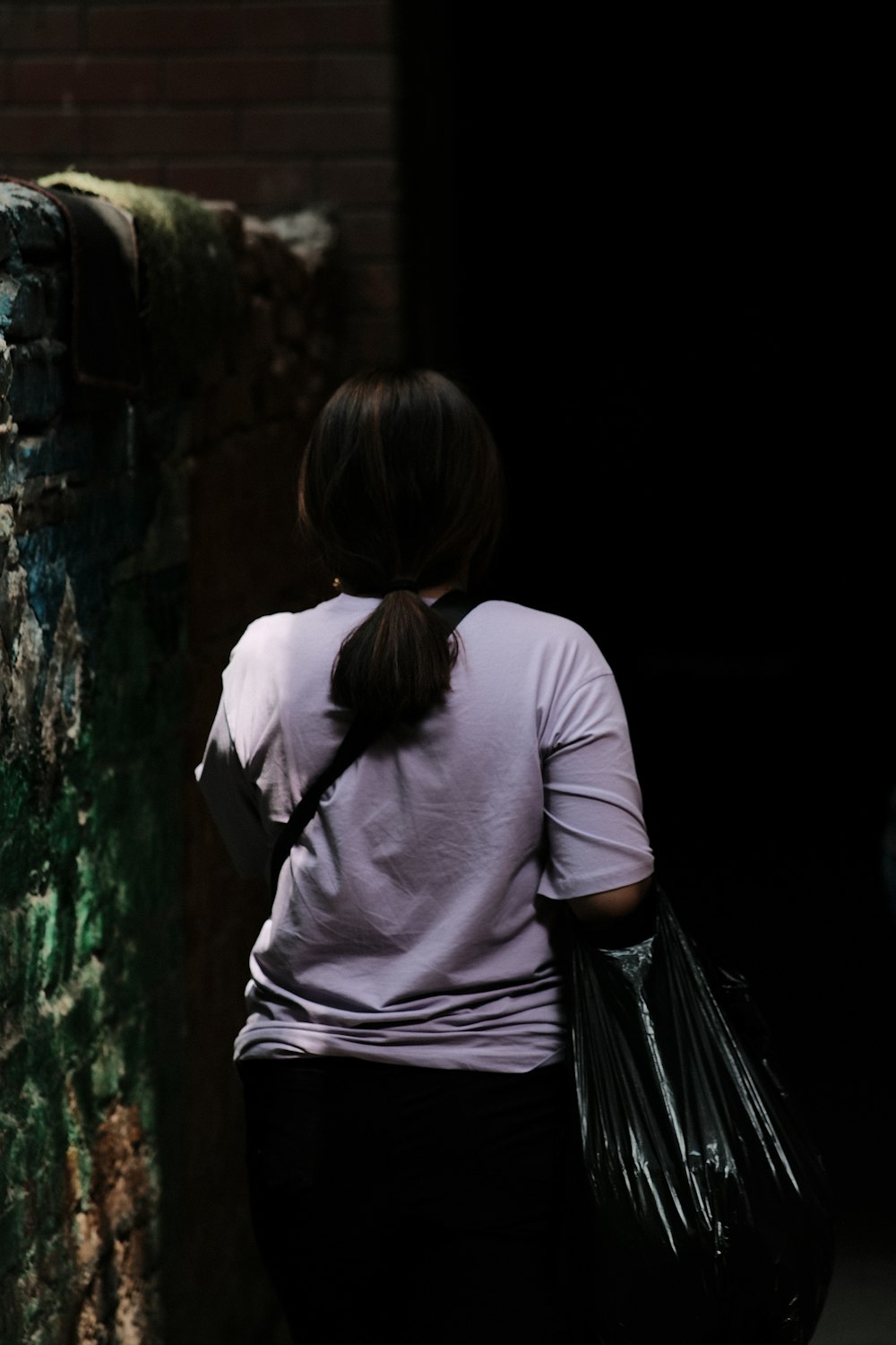 a woman walking down a street carrying a black bag