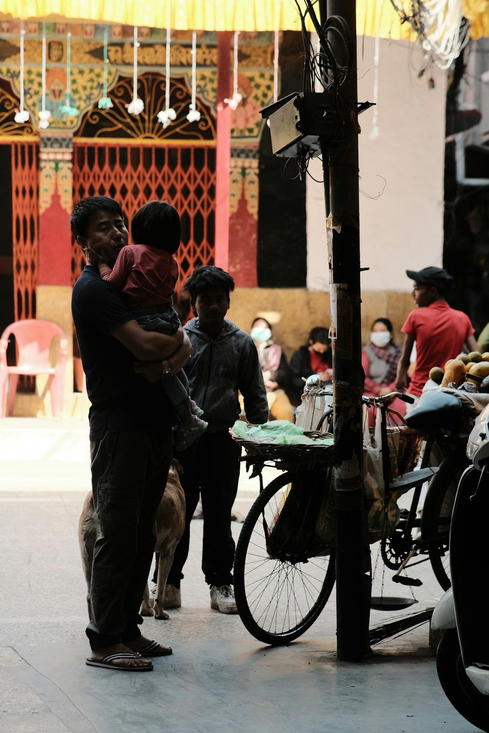 a man holding a child standing next to a bike