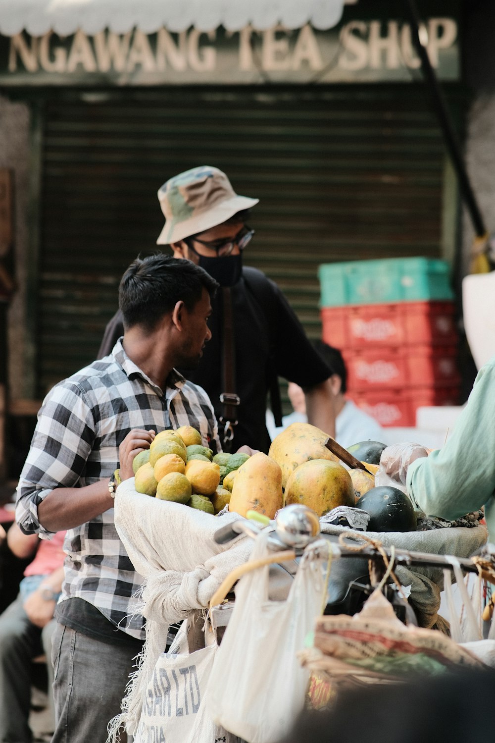 a man standing next to a pile of fruit