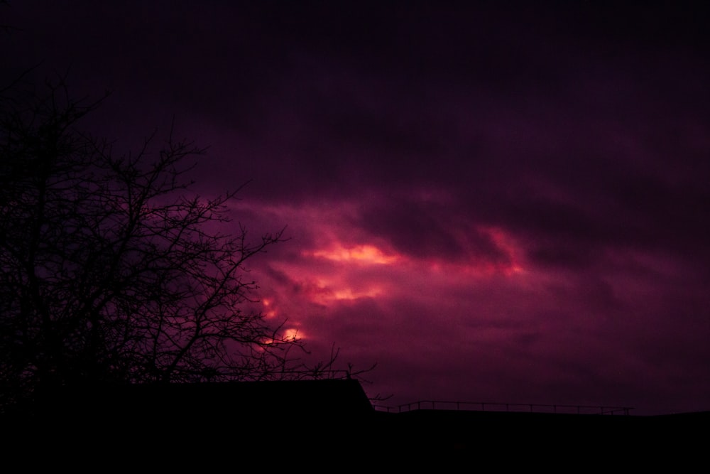 a purple sky with clouds and a fence