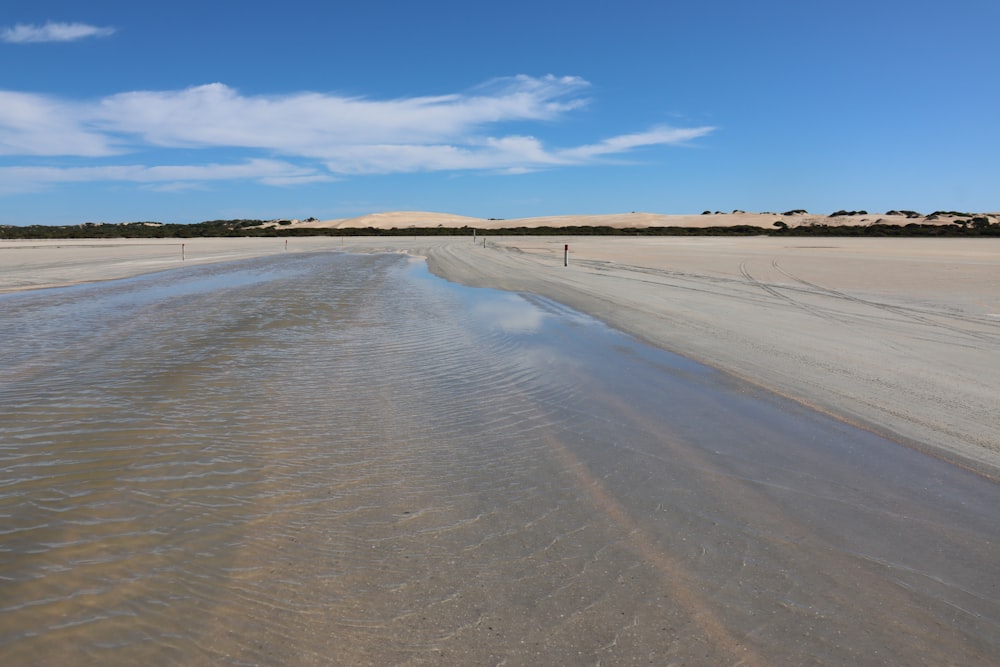 uma praia de areia com um corpo de água no meio dela