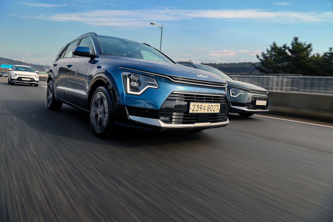 a couple of cars driving down a highway, Kia Niro driving on highway under the blue sky
