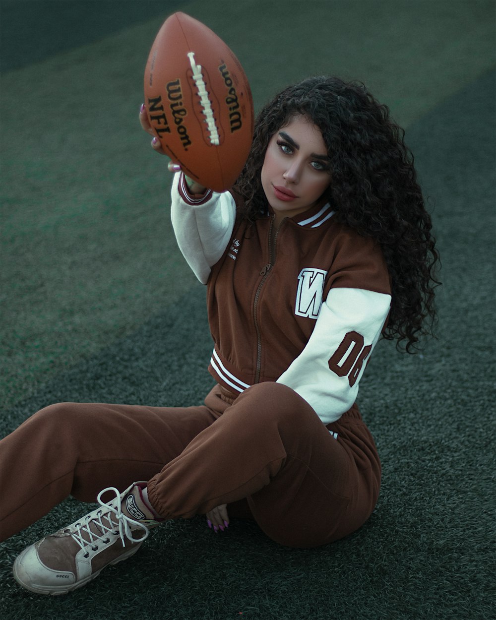 a woman sitting on the ground holding a football