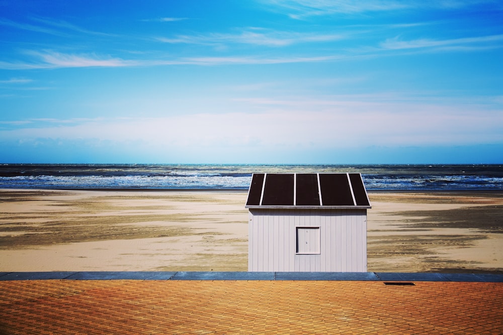 a small white building sitting on top of a sandy beach