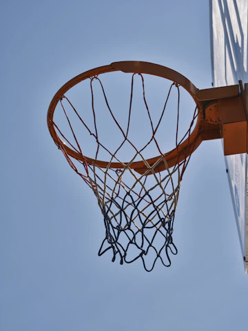 Close-up of a sleek basketball hoop against a clear blue sky.