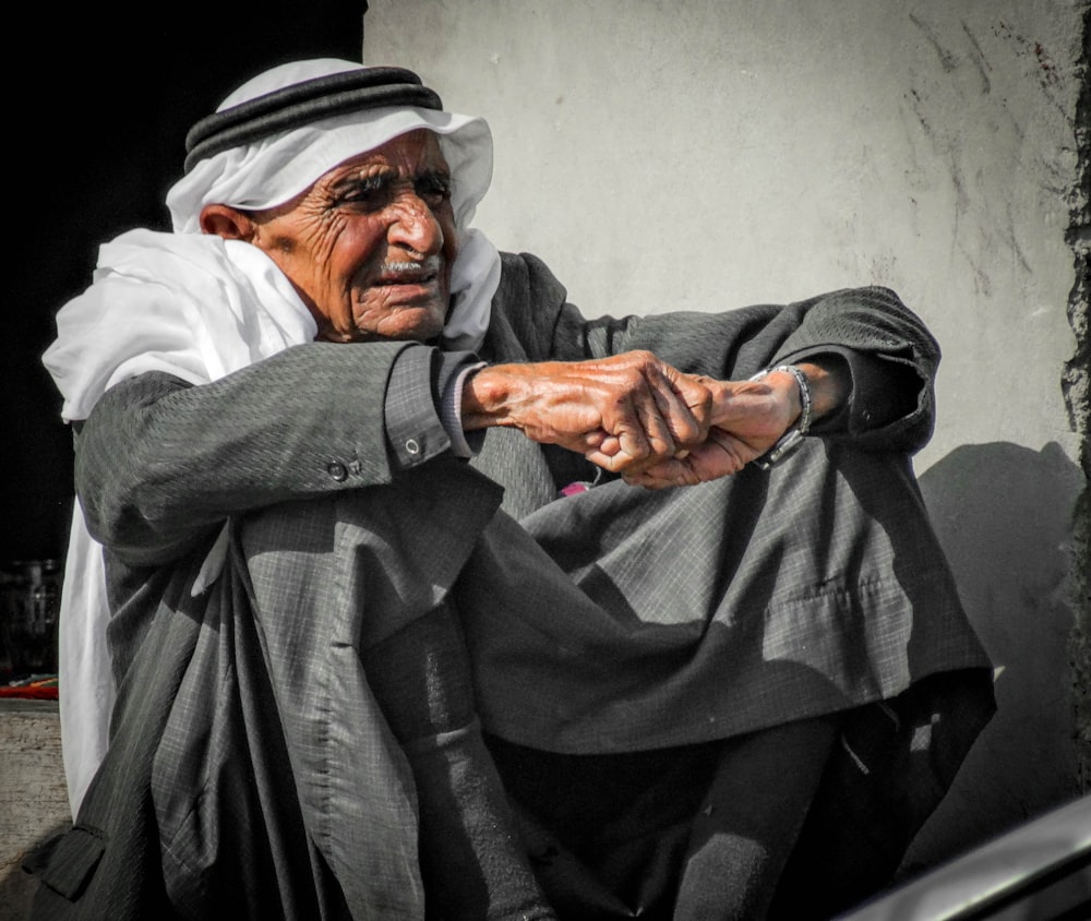 an old man sitting on the ground with his hand on his knee